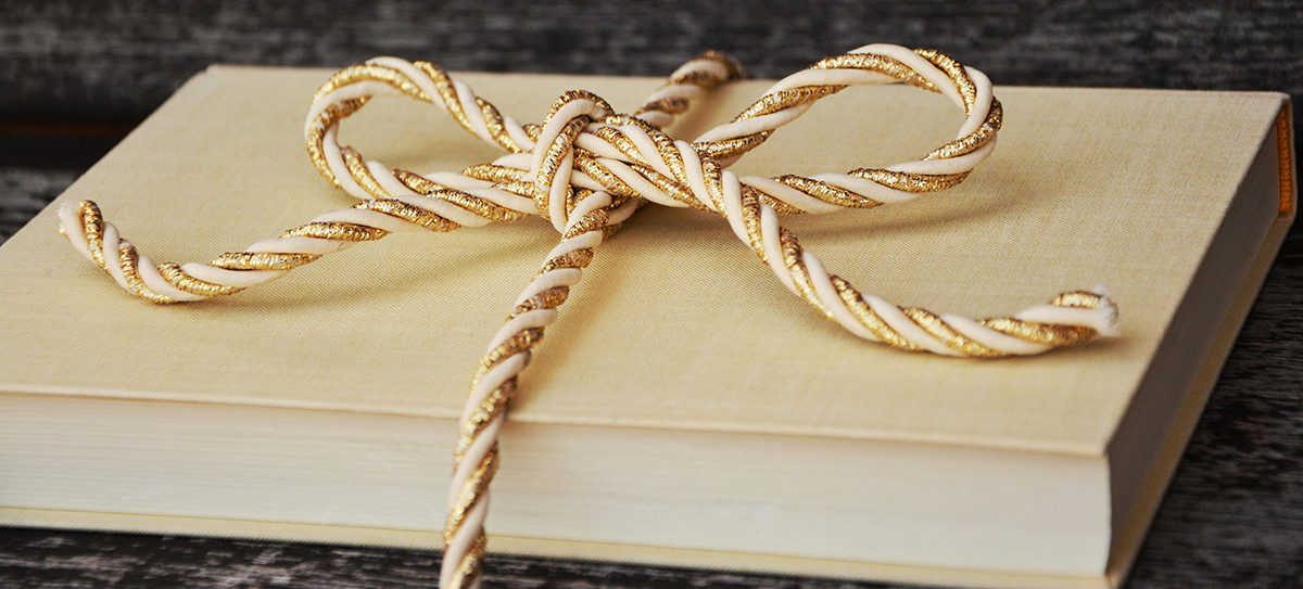 Un livre entouré d'un beau lacet or et blanc, noué sur le dessus.